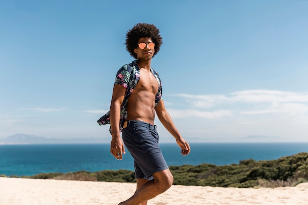 Hübscher Afroamerikanermann, der auf Strand geht