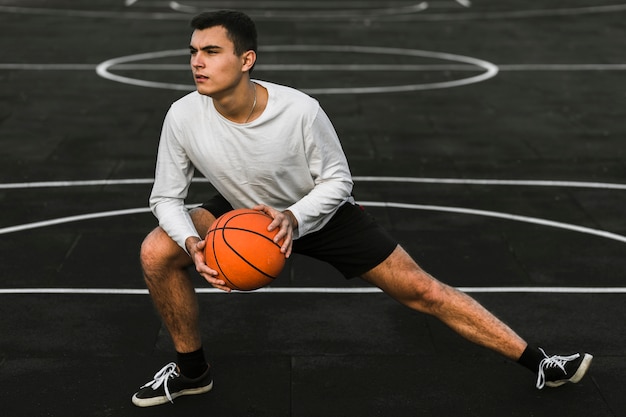 Hübscher Athlet, der auf Basketballplatz ausdehnt