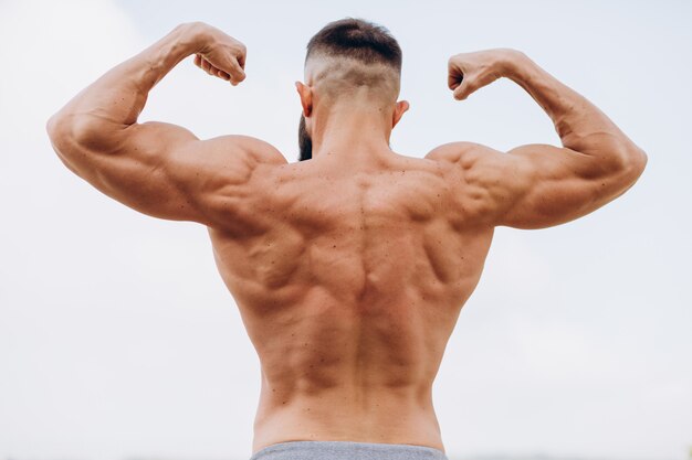 Hubscher Bartiger Bodybuilder Mann Mit Perfektem Muskelkorper Der Draussen Auf Dem Himmelhintergrund Aufwirft Starker Mann Mit Nacktem Oberkorper Der Wegschaut Blick Von Hinten Premium Foto