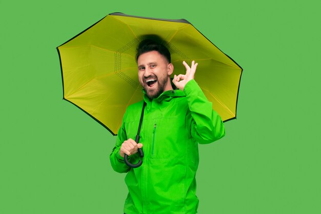 Hübscher bärtiger junger Mann, der Regenschirm hält