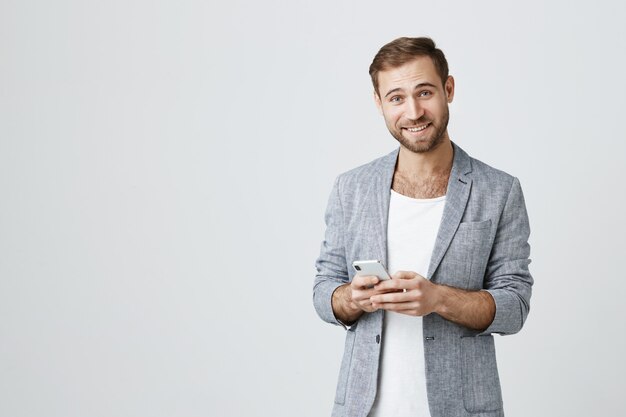 Hübscher bärtiger Mann in der Jacke mit Handy