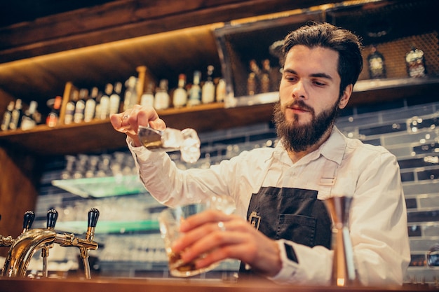 Hübscher Barmixer, der das Trinken und die Cocktails an einem Zähler macht