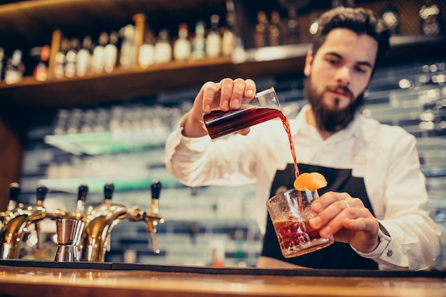 Hübscher Barmixer, der das Trinken und die Cocktails an einem Zähler macht