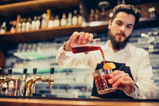 Hübscher Barmixer, der das Trinken und die Cocktails an einem Zähler macht