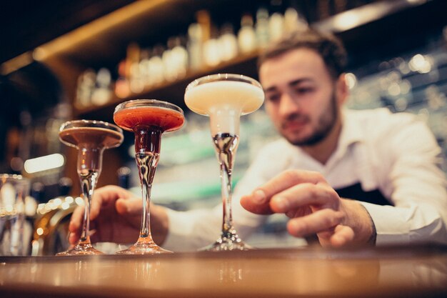 Hübscher Barmixer, der das Trinken und die Cocktails an einem Zähler macht