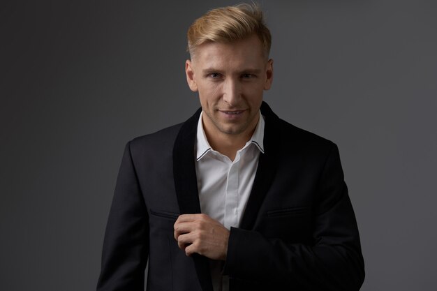 Hübscher blonder junger Mann, der am Studio aufwirft