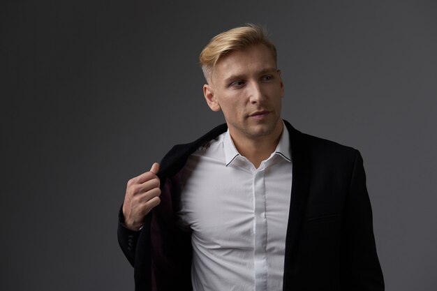 Hübscher blonder junger Mann, der am Studio aufwirft