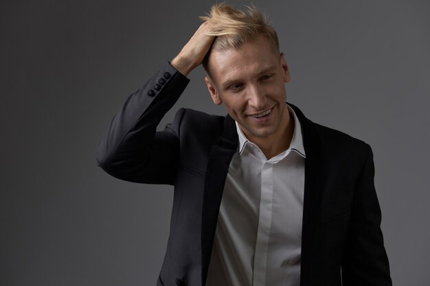 Hübscher blonder junger Mann, der am Studio aufwirft