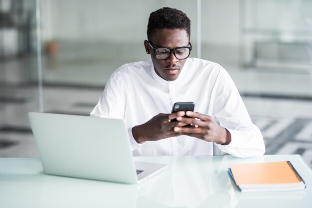 Hübscher Büroangestellter, der ein paar Minuten Pause hat und SMS auf Smartphone schreibt