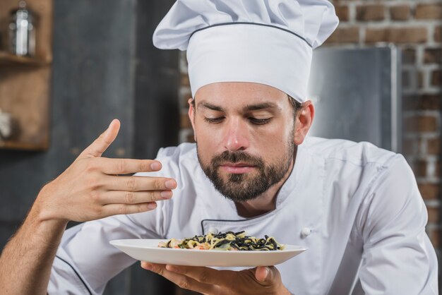 Hübscher Chef, der Geruch des gekochten Tellers schnüffelt