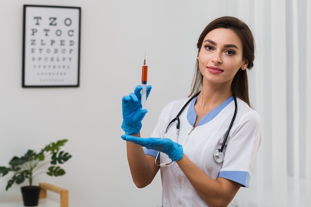 Kostenloses Foto hübscher doktor, der eine spritze anhält