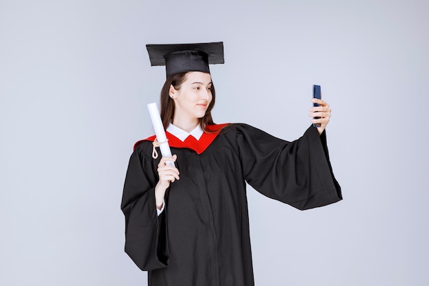 Hübscher Doktorand im Kleid, das Selfie macht. Foto in hoher Qualität