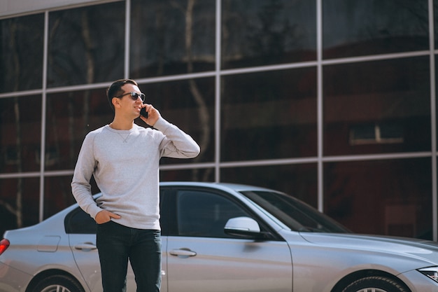 Hübscher erfolgreicher mann mit dem auto mit mobiltelefon