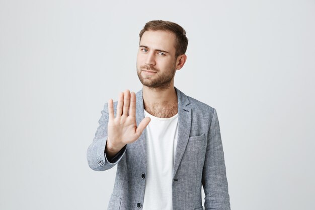 Hübscher ernsthafter Mann sagen aufhören. Handfläche im Verbot zeigen