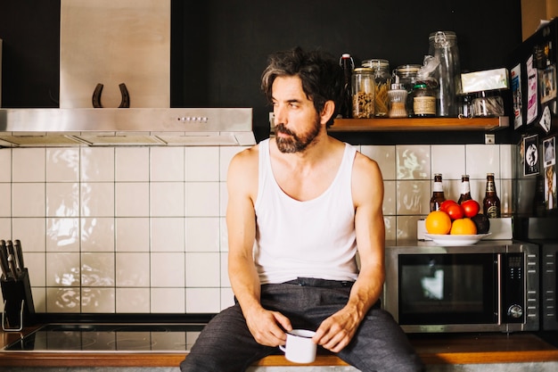 Kostenloses Foto hübscher erwachsener mann träumt in der küche