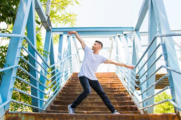 Hübscher flexibler junger Mann, der Hip-Hop auf Treppenhaus tut
