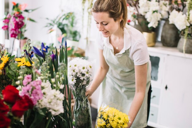 Hübscher Florist, der Blumensträuße im Geschäft vereinbart