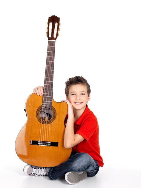 Hübscher fröhlicher Junge mit der Akustikgitarre