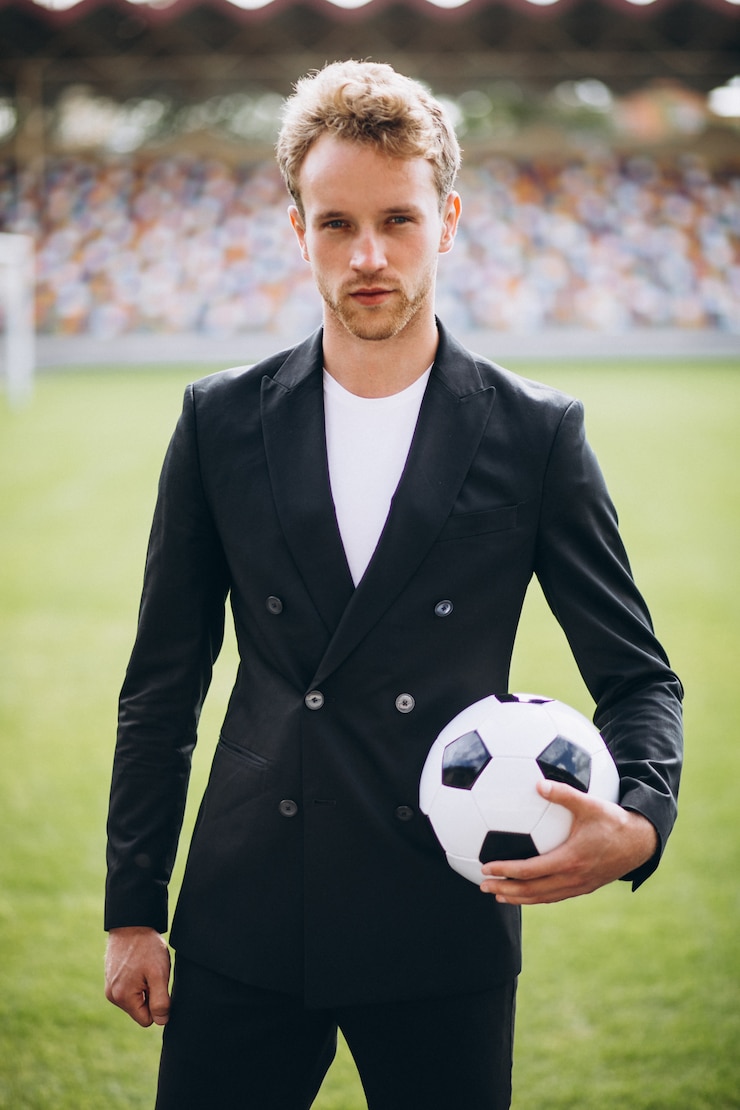 Kostenlose Foto hübscher fußballspieler am stadion im anzug