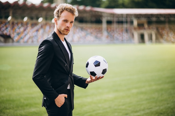 Kostenlose Foto hübscher fußballspieler am stadion im anzug