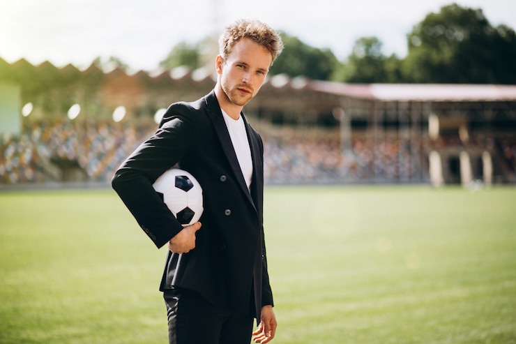 Kostenlose Foto hübscher fußballspieler am stadion im anzug