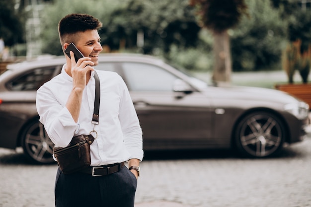 Hübscher Geschäftsmann, der am Telefon durch sein Auto spricht