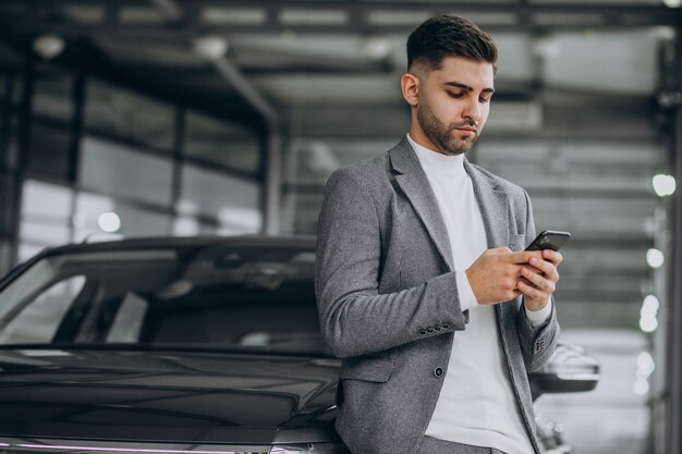 Hübscher Geschäftsmann, der am Telefon in einem Autohaus spricht