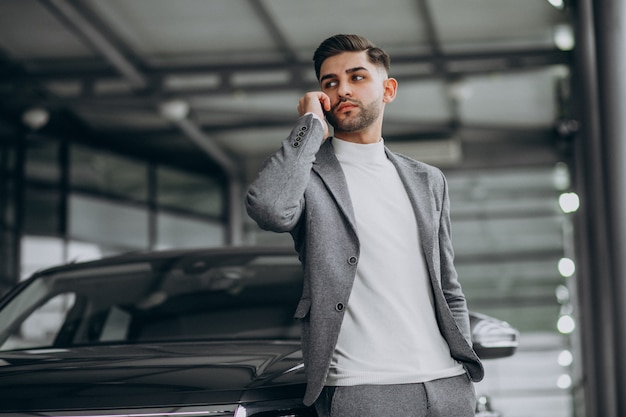 Hübscher Geschäftsmann, der am Telefon in einem Autohaus spricht