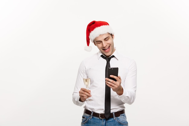 Hübscher Geschäftsmann, der am Telefon spricht und Glas Champagner hält, der Chirstmas feiert