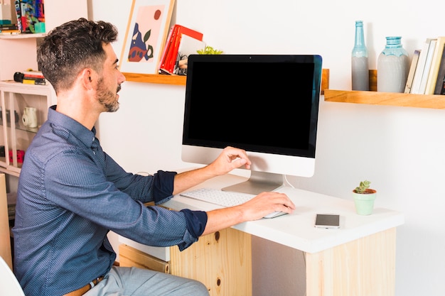 Hübscher Geschäftsmann, der an Computer an seinem Arbeitsplatz arbeitet