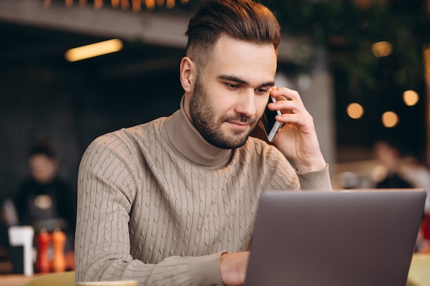 Hübscher Geschäftsmann, der an Computer arbeitet und Kaffee in einem Café trinkt