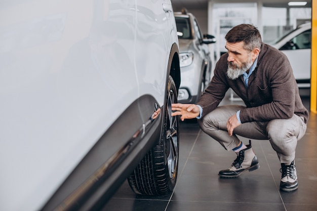 Hübscher Geschäftsmann, der ein Auto im Autohaus wählt