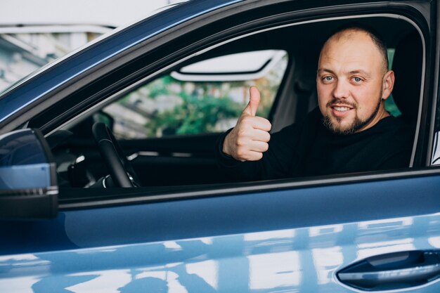 Hübscher Geschäftsmann, der ein Auto in einem Autoausstellungsraum wählt