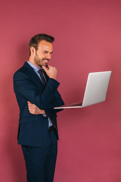 Hübscher geschäftsmann, der in einem laptop arbeitet