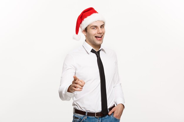Hübscher Geschäftsmann, der Weihnachtsmütze zeigt Finger auf Weiß zeigt.
