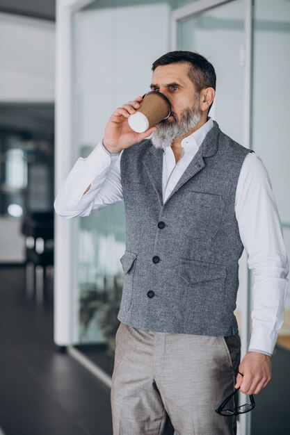 Hübscher Geschäftsmann trinkt Kaffee im Büro