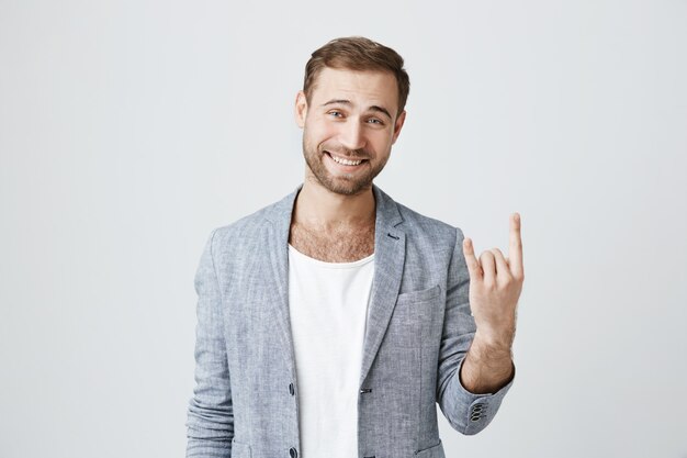 Hübscher glücklicher bärtiger Mann zeigen Rock-n-Roll-Geste