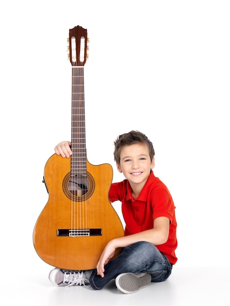 Hübscher glücklicher Junge mit der Akustikgitarre lokalisiert auf weißem Hintergrund