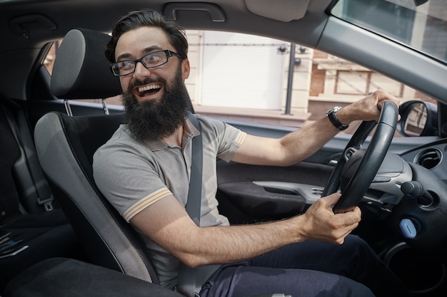 Kostenloses Foto hübscher, glücklicher mann, der das auto fährt