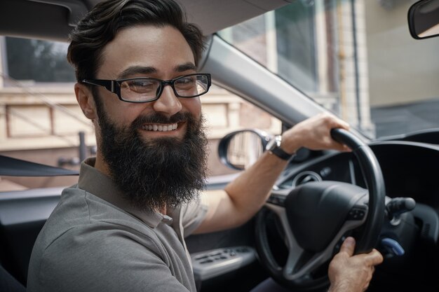 Hübscher, glücklicher Mann, der das Auto fährt