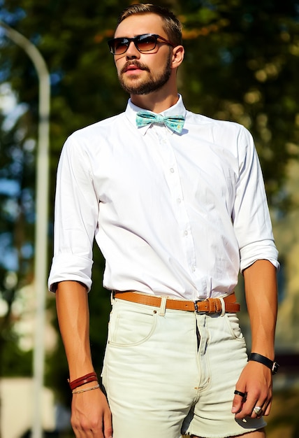 Hübscher Hipster-Modellmann in der stilvollen Sommerkleidung, die in der Sonnenbrille aufwirft