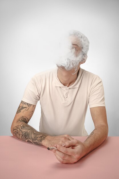 Hübscher Hipstermann, der Zigarette zu Hause raucht