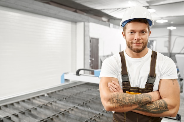 Hübscher Ingenieur, der auf Fabrik nahe Plasmaschneider aufwirft.