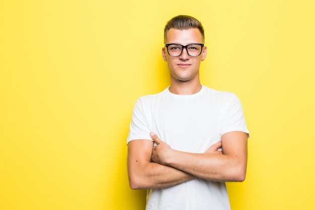 Hübscher Junge hält seine Arme verschränkt, gekleidet in weißes T-Shirt und transparente Brille