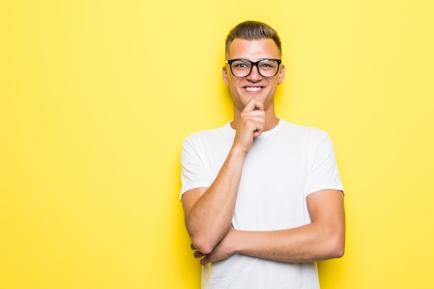 Hübscher Junge hält seine Hand unter seinem Kinn, gekleidet in weißes T-Shirt und transparente Brille