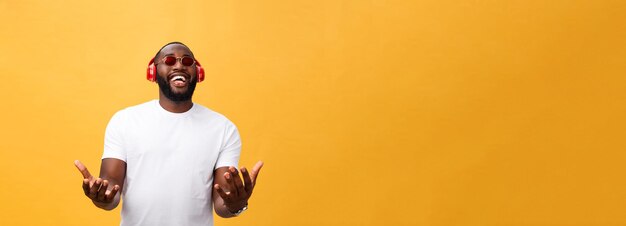 Hübscher junger afrikanisch-amerikanischer Mann, der mit Musik auf seinem mobilen Gerät zuhört und lächelt, isoliert o