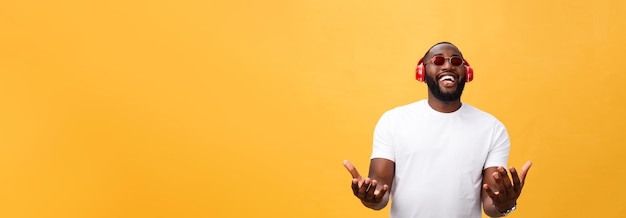 Hübscher junger afrikanisch-amerikanischer Mann, der mit Musik auf seinem mobilen Gerät zuhört und lächelt, isoliert o