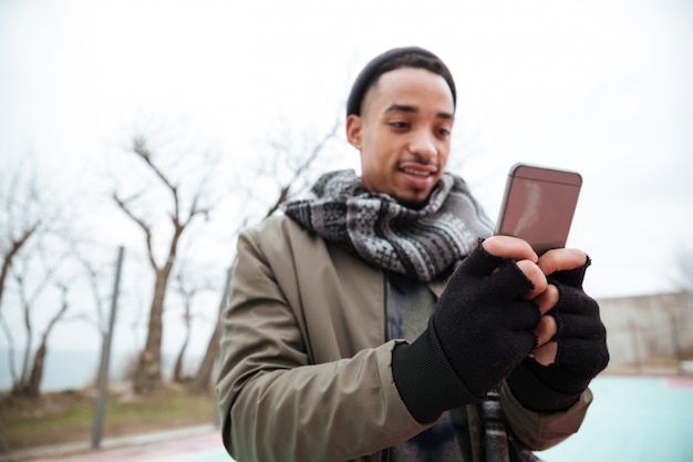 Hübscher junger afrikanischer Mann, der per Telefon plaudert.