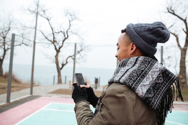 Hübscher junger afrikanischer Mann, der per Telefon plaudert.