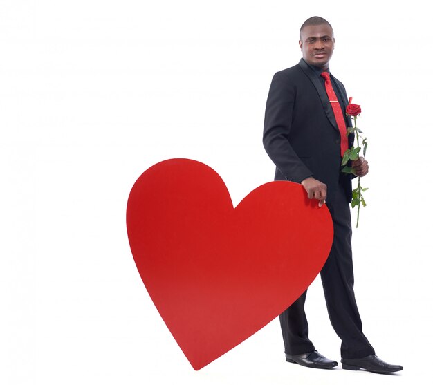 Hübscher junger afrikanischer Mann, der rote Rose hält